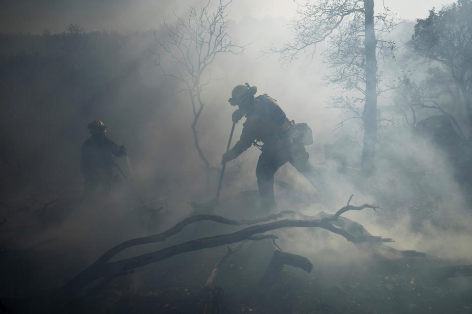 A firefighter extinguishes hotspots while battling the Olinda Fire in Anderson, Calif., Sunday, Oct. 25, 2020. (AP Photo/Noah Berger)