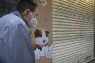 CORRECTS TO SAY 2,000 SMALL ANIMALS, NOT 2,000 HAMSTERS - A man walks by a pet shop that was closed after pet hamsters were, authorities said, tested positive for the coronavirus, in Hong Kong, Tuesday, Jan. 18, 2022. Hong Kong authorities said Tuesday that they will kill about 2,000 small animals, including hamsters, after several tested positive for the coronavirus at the pet store where an employee was also infected. (AP Photo/Kin Cheung)