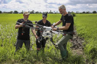 In this photo taken Wednesday, Oct. 30, 2019, Dr. Bart Knols, medical entomologist from the Dutch Malaria Foundation and lead researcher of the Anti-Malaria Drones program, left, Eduardo Rodriguez, of drone manufacturer DJI, center, and Guido Welter, a consultant from the program, prepare a drone to spray the breeding grounds of malaria-carrying mosquitoes, at Cheju paddy farms in the southern Cheju region of the island of Zanzibar, Tanzania. Drones spraying a silicone-based liquid that spreads across the large expanses of stagnant water where malaria-carrying mosquitoes lay their eggs, are being tested to help fight the disease on the island of Zanzibar, off the coast of Tanzania. (AP Photo/Haroub Hussein)