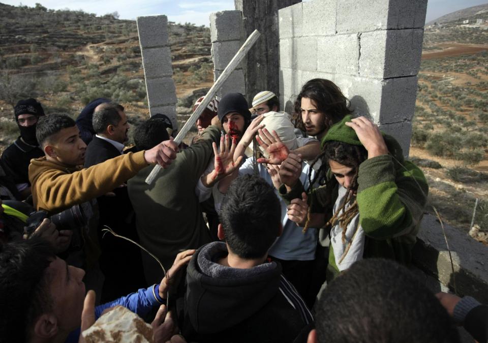 Palestinians hit Israeli settlers while others try to stop them before a group of settlers were detained by Palestinian villagers in a building under construction near the West Bank village of Qusra, southeast of the city of Nablus, Tuesday, Jan. 7, 2014. Palestinians held more than a dozen Israeli settlers for about two hours Tuesday in retaliation for the latest in a string of settler attacks on villages in the area, witnesses said. The military said the chain of events apparently began after Israeli authorities removed an illegally built structure in Esh Kodesh, a rogue Israeli settlement in the area. In recent years, militant settlers have often responded to any attempts by the Israeli military to remove parts of dozens of rogue settlements, or outposts, by attacking Palestinians and their property. The tactic, begun in 2008, is known as "price tag." (AP Photo/Nasser Ishtayeh)