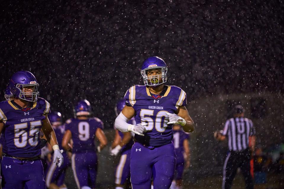 Sep 9, 2022; Queen Creek, Arizona, USA; As rain continues to fall Queen Creek Bulldogs junior defensive tackle Tayo Omotinugbon (50) returns to the sidelines at Queen Creek High School. Mandatory Credit: Alex Gould/The Republic