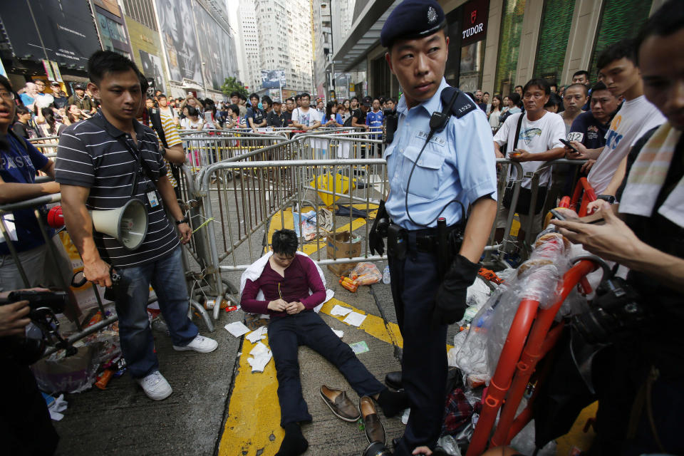 A police guards over a pro-democracy student protester who collapsed during scuffles with locals trying to remove the barricades blocking local streets in Causeway Bay, Hong Kong, Friday, Oct. 3, 2014. (AP Photo/Wally Santana)