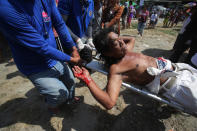 A Filipino devotee who was nailed to the cross is carried by medical personnel after blood comes out of his wounds during a re-enactment of the crucifixion of Jesus Christ in San Pedro Cutud village, Pampanga province, northern Philippines on Friday, April 18, 2014. Church leaders and health officials have spoken against the practice which mixes Roman Catholic devotion with folk belief, but the annual rites continue to draw participants and huge crowds. (AP Photo/Aaron Favila)