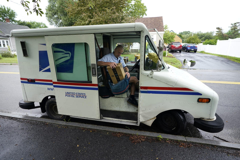 U.S. Postal Service carrier John Graham packs his mail bag after parking a 28-year-old delivery truck, Wednesday, July 14, 2021, in Portland, Maine. The Postal Service’s aging fleet of trucks is soldiering on even as a contract for greener replacement vehicles is being challenged. The primary fleet of vehicles that were delivered starting in 1987 is due to be replaced under a new contract, but the winning bid is being challenged. (AP Photo/Robert F. Bukaty)