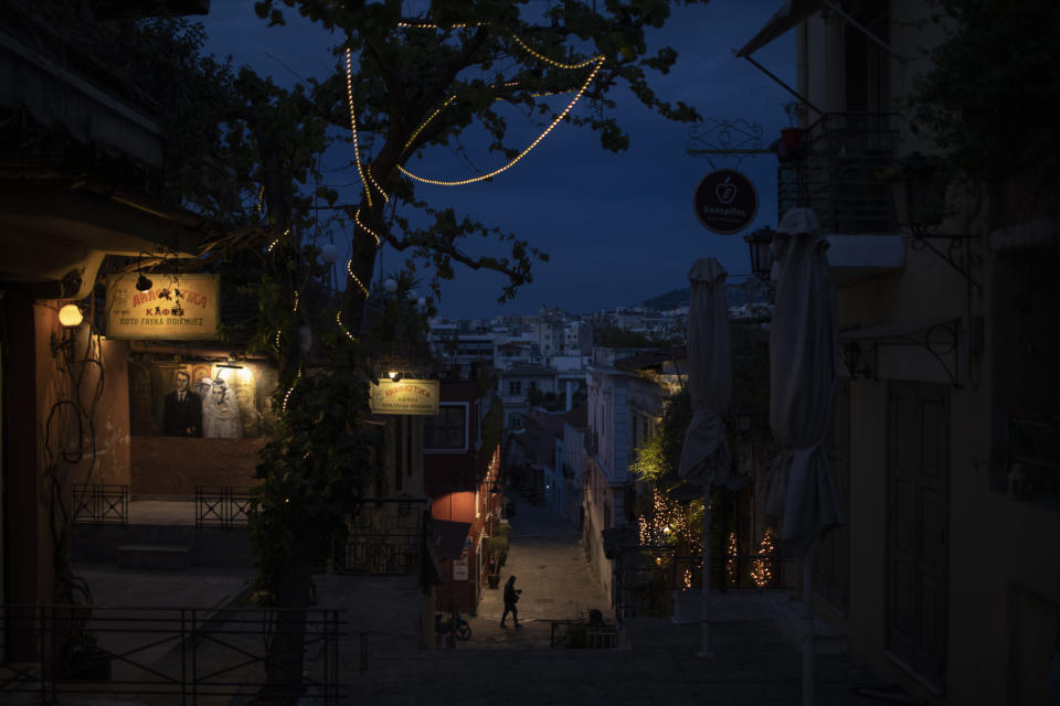 A man walks in the Plaka district of Athens past closed coffee shop and restaurants during a lockdown order by the Greek government to to avoid the spread of the coronavirus in Athens, on Tuesday, April 14, 2020. (AP Photo/Petros Giannakouris)