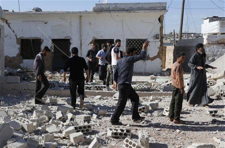People inspect a site hit by what activists said were barrel bombs dropped by forces loyal to Syria's President Bashar al-Assad in al-Letmana village in Hama province May 1, 2014. REUTERS/Badi Khlif