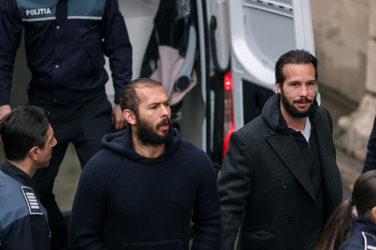 Andrew Tate and his brother Tristan are escorted by police officers inside the headquarters of the Bucharest Court of Appeal (via REUTERS)