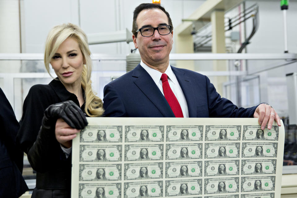 U.S. Treasury secretary Steve Mnuchin and his wife, Louise Linton, pose with a sheet of $1 bills at the U.S. Bureau of Printing and Engraving. (Bloomberg via Getty Images)