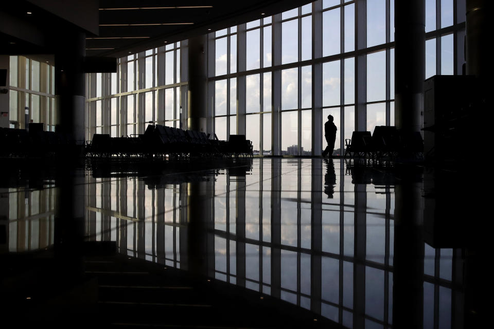 FILE - In this June 1, 2020 file photo, a woman looks through a window at a near-empty terminal at an airport in Atlanta. The coronavirus pandemic has taken a harsh toll on the mental health of young Americans, according to a new poll that finds adults under 35 especially likely to report negative feelings or experience physical or emotional symptoms associated with stress and anxiety. (AP Photo/Charlie Riedel, File)