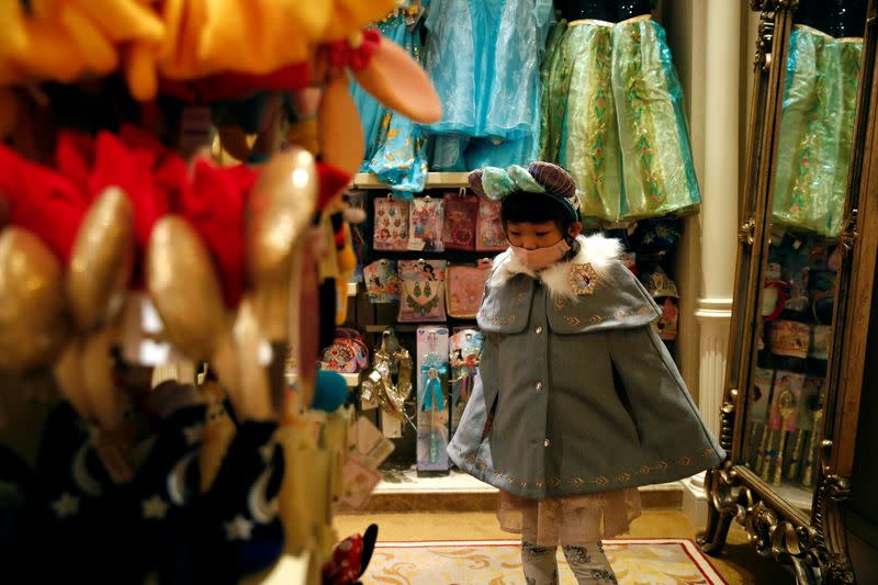 A child wears mask as she tries a themed ears at a souvenir shop in Disneyland hotel after Hong Kong Disneyland that has been closed, following the coronavirus outbreak in Hong Kong