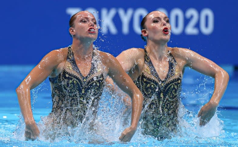 Two swimmers emerge from the water with their eyes open