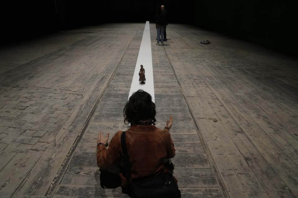 A visitor gestures as he sits in front of he installation "Due qui to hear," by artist Massimo Bartolini at the Italian pavilion at the 60th Biennale of Arts exhibition in Venice, Italy, Tuesday, April 16, 2024. The Venice Biennale contemporary art exhibition opens Saturday for its six-month run through Nov. 26. (AP Photo/Luca Bruno)