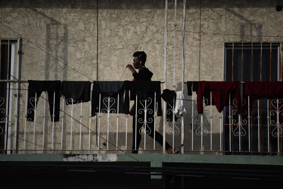 A Haitian woman walks past clothes drying on a rail at an apartment where a group of Haitians live, in Tijuana, Mexico, Thursday, Nov. 22, 2018. The border town welcomed thousands of Haitians to pursue a scaled-down American dream south of the border after the US closed its doors on them more than two years ago. (AP Photo/Ramon Espinosa)