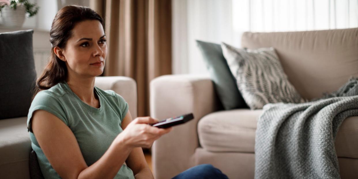 woman at home watching tv with remote control