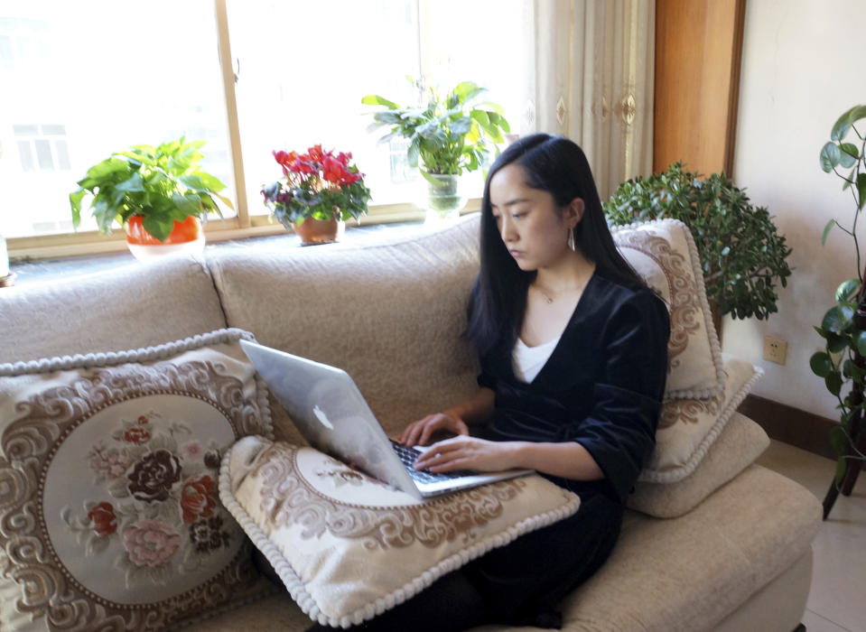 In this Wednesday, Feb. 12, 2020, photo released by Maggie Zhang, Zhang uses a laptop computer at her parents' home in in the northwestern city of Zhangye in Gansu province. Zhang, founder of SheTalks, a company in Beijing that organizes events for women, is working out of her parents' apartment after she went back for the Lunar New Year and said she might stay through March. (Maggie Zhang via AP)