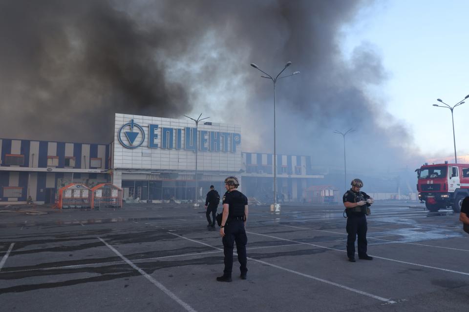 Law enforcement officers stand outside a supermarket after it was hit with two Russian glide bombs in Kharkiv on May 25, 2024.
