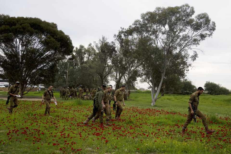 Soldados israelíes caminan sobre un campo cubierto de flores silvestres en Reim, en el sur de Israel, el lunes 12 de febrero de 2024. (AP Foto/Maya Alleruzzo)