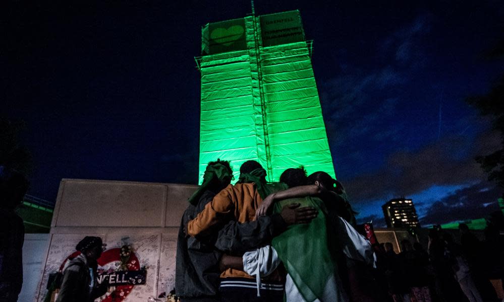 People embrace each other at the foot of Grenfell Tower in west London on the first anniversary of the fire that killed 72 people.