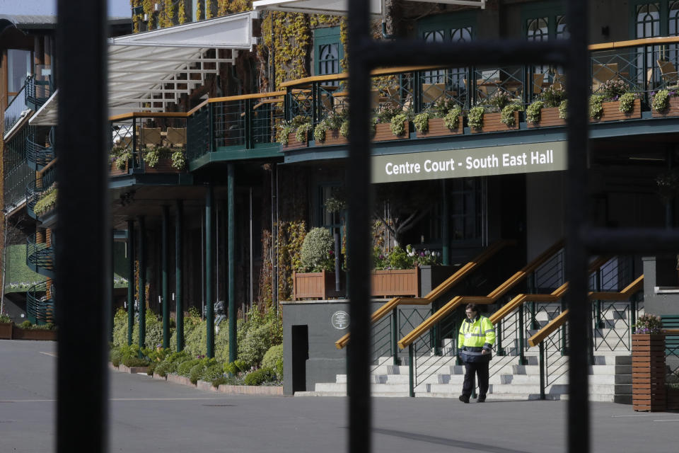 Un empleado de seguridad dentro de la entrada principal al torneo de Wimbledon, el miércoles 1 de abril de 2020. (AP Foto/Kirsty Wigglesworth)