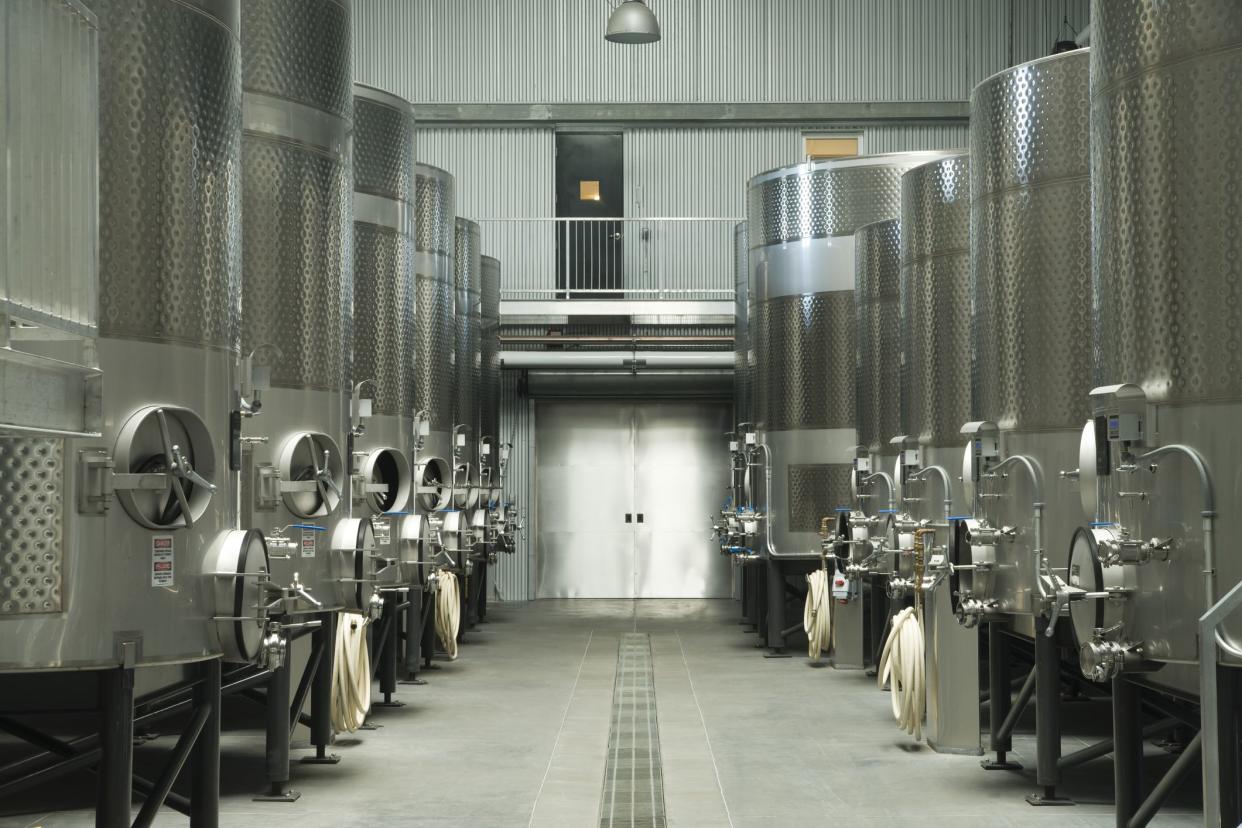 Modern winery facility utilizing stainless steel containers compared to old style wooden barrels.