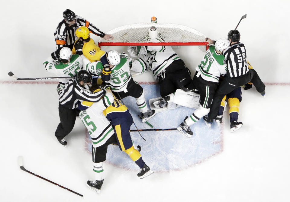 Dallas Stars goaltender Ben Bishop takes refuge in the net as players fight during the first period in Game 2 of an NHL hockey first-round playoff series against the Nashville Predators, Saturday, April 13, 2019, in Nashville, Tenn. (AP Photo/Mark Humphrey)