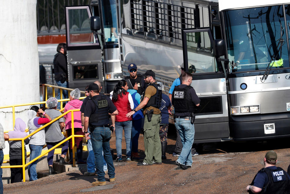 Handcuffed workers are escorted into a bus for transportation to a processing center following a raid by U.S. immigration officials at a Koch Foods Inc., plant in Morton, Miss. on Aug. 7, 2019.