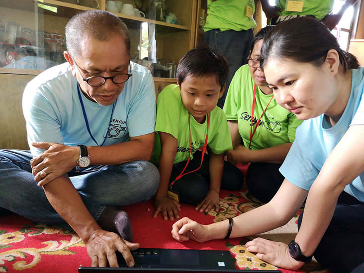 Lok (left) reviews photographs taken by participants after a group photoshoot in Kuching.