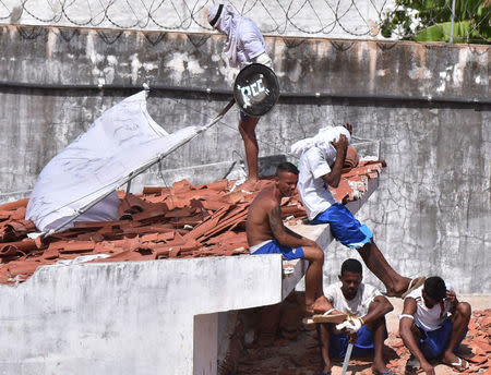 An inmate uses a shield with the initials PCC to protect himself after a new uprising broke out at Alcacuz prison in Natal, Rio Grande do Norte state, Brazil, January 16, 2017. PCC (First Command of the Capital) are the initials of Brazil's most powerful drug gang. REUTERS/Josemar Goncalves