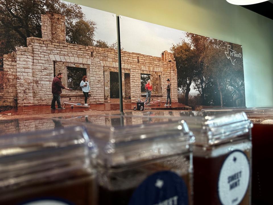On the back wall of HTeaO in Dripping Springs, a photo of the Sanders family playing cornhole with the company logo attached is visible to customers entering the store.