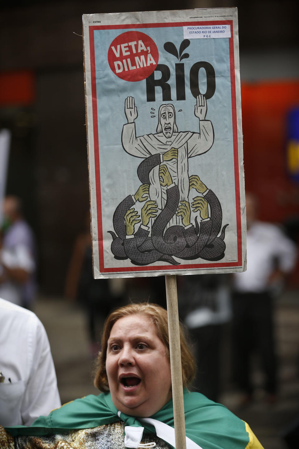 A woman protests with a sign that reads in Portuguese "Veto Dilma, Rio" during a march in Rio de Janeiro, Brazil, Monday, Nov. 26, 2012. Thousands of demonstrators gathered in downtown Rio de Janeiro for a march against legislation that officials here insist would strip this oil-producing state of much of its income from the energy sector. The protesters are calling on President Dilma Rousseff to veto the measure. (AP Photo/Victor R. Caivano)