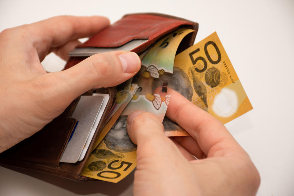 Hands holding leather wallet with Australian $50 banknotes wages.