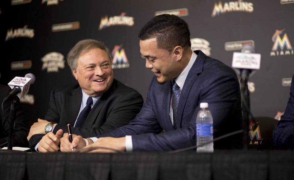 Jeffrey Loria (izq.) sonríe mientras observa la firma histórica de Giancarlo Stanton. (AP Photo/J Pat Carter)