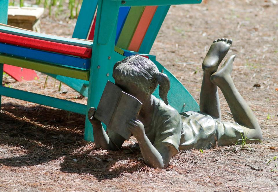 A sculpture of a girl buried in a book at Bookworm Garden, Wednesday, May 10, 2023, in Sheboygan, Wis.