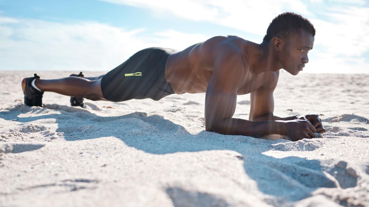  A man performing a plank on the beach as part of an abs workout  