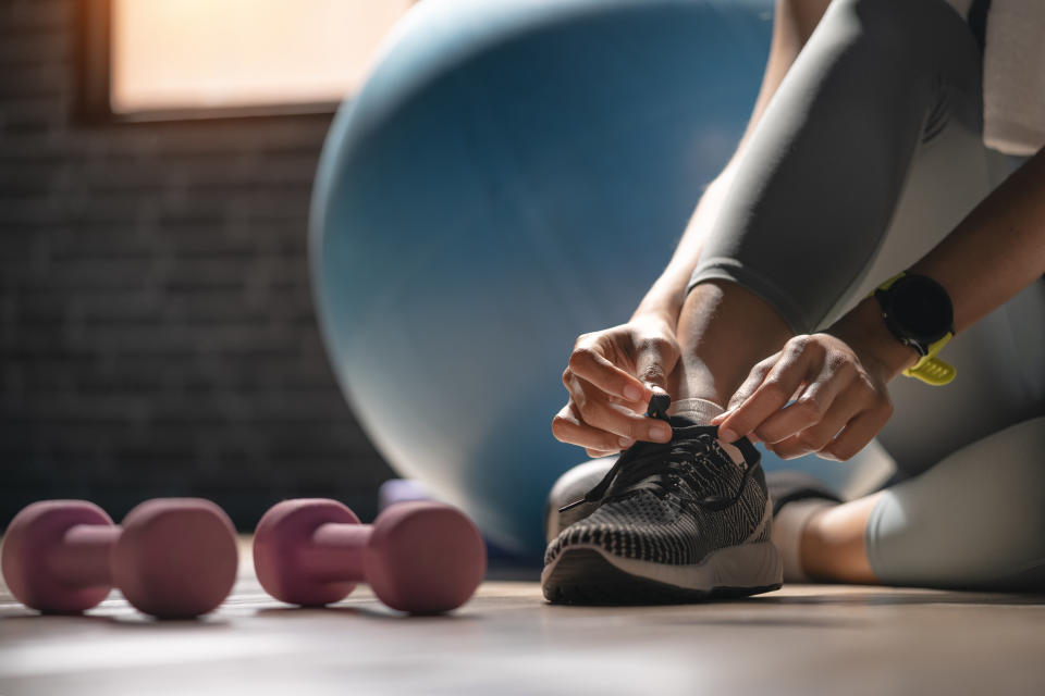 Frau bindet ihre Schnürsenkel im Fitnessstudio, Nahaufnahme von ihrem Fuß