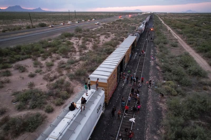 Migrants travelling by train to Ciudad Juarez wait near train wagons while being stranded near Villa Ahumada