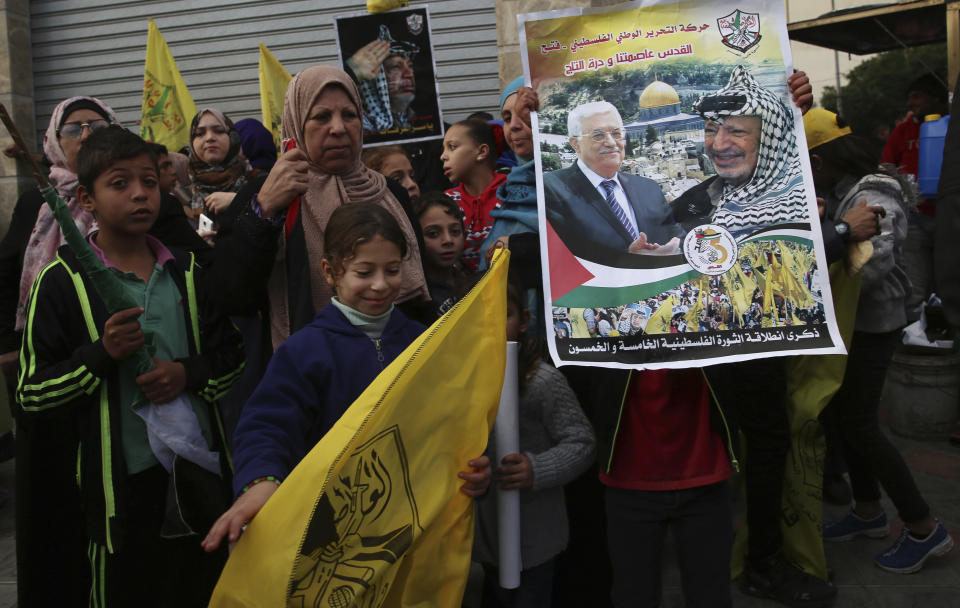 Palestinian Fatah supporters hold portraits of Palestinian President Mahmoud Abbas and late Palestinian President Yasser Arafat during a celebration marking the 55th anniversary of the Fatah movement, in Gaza City, Wednesday, Jan. 1, 2020. Tens of thousands of Palestinians took to the streets in Gaza Wednesday to mark the 55th anniversary of President Mahmoud Abbas' Fatah movement, as the territory's Hamas rulers permitted the event for the first time in years. (AP Photo/Adel Hana)