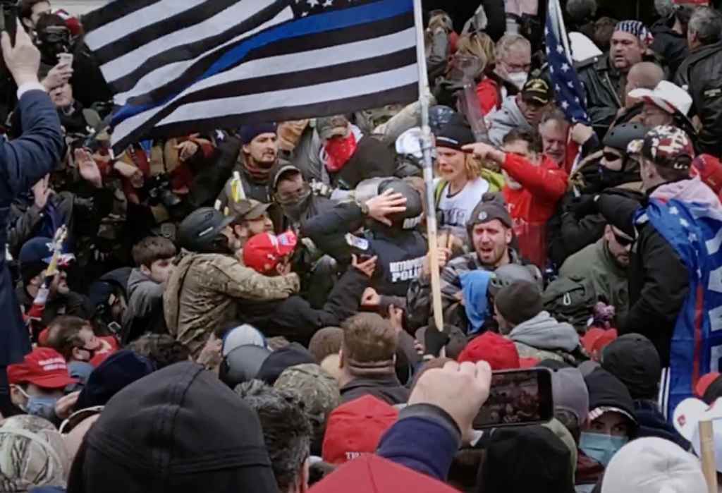 Officer Michael Fanone being assaulted by pro-Trump mob beneath a ‘Blue Lives Matter’ flag outside the US Capitol on 6 January 2021 (HBO)