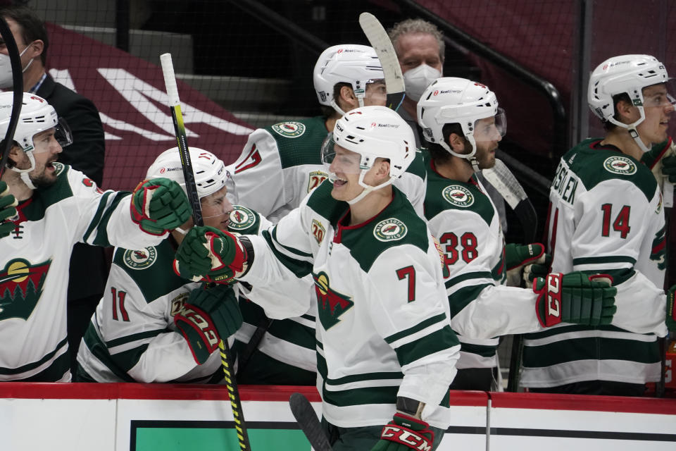 Minnesota Wild center Nico Sturm, front, is congratulated as he passes the team box after scoring a goal against the Colorado Avalanche during the third period of an NHL hockey game Wednesday, Feb. 24, 2021, in Denver. (AP Photo/David Zalubowski)