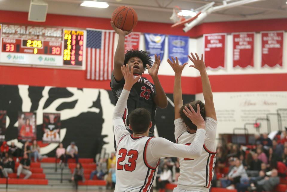 West Allegheny's Justin Manns (25) goes for a layup over the head of Moon's Michael Santicola (23) and Luca Michnowicz (2) during the second half Tuesday night at Moon Area High School.