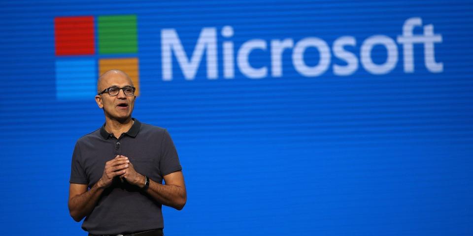 Microsoft CEO Satya Nadella with the word &quot;Microsoft&quot; and the Microsoft logo displayed behind him