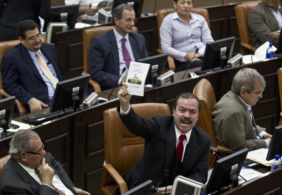 Legislator Armando Herrera of the Liberal Independent Party, PLI, holds a copy of Nicaragua's Constitution as a way to show his opposition to an amendment that includes eliminating presidential term limits, at the National Assembly, Tuesday, Jan. 28, 2014, in Managua, Nicaragua. Lawmakers have approved constitutional changes that would allow President Daniel Ortega to be re-elected indefinitely, a move that his critics say is designed to keep the Sandinista leader in power for life. (AP Photo/Esteban Felix)