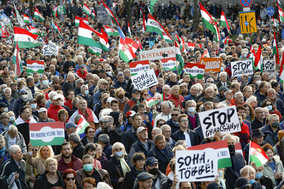 People hold banners that read "Never Again" during a march marking the 65th anniversary of the 1956 Hungarian revolution, in Budapest, Hungary, Saturday, Oct. 23, 2021. Thousands of supporters of Prime Minister Viktor Orban, who is expected to deliver a speech marking the 65th anniversary of the 1956 Hungarian revolution, march in Budapest, Hungary to demonstrate loyalty to his right-wing government. (AP Photo/Laszlo Balogh)