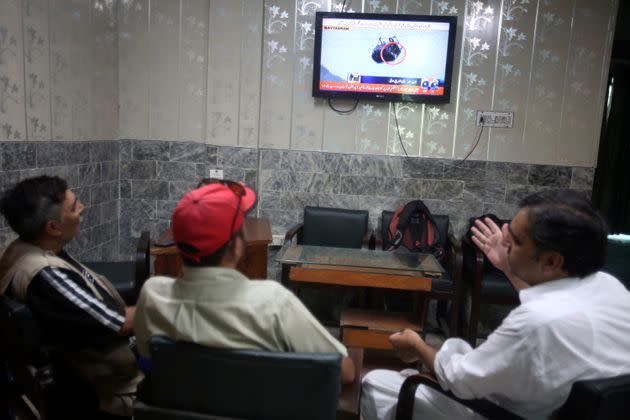 Members of media watch a news channel covering the eight people trapped in a cable car on Aug. 22 at an office in Peshawar, Pakistan.