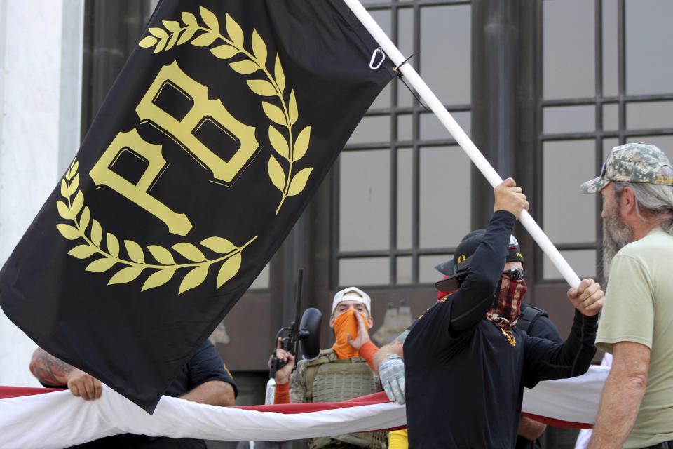 FILE - A protester carries a Proud Boys banner while other members start to unfurl a large U.S. flag in front of the Oregon State Capitol in Salem, Ore., on Sept. 7, 2020. Over the past decade, Oregon experienced the sixth-highest number of extremist incidents in the nation, despite being 27th in population, according to an Oregon Secretary of State report. Now, the state Legislature is considering a bill that, experts say, would create the nation's most comprehensive law against paramilitary activity. (AP Photo/Andrew Selsky, File)