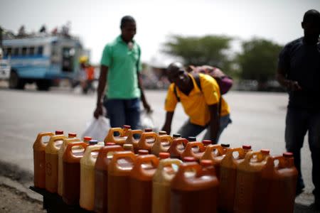 Men walk past a stand displaying containers with fuel on the outskirts of Port-au-Prince, Haiti, July 12, 2018. REUTERS/Andres Martinez Casares