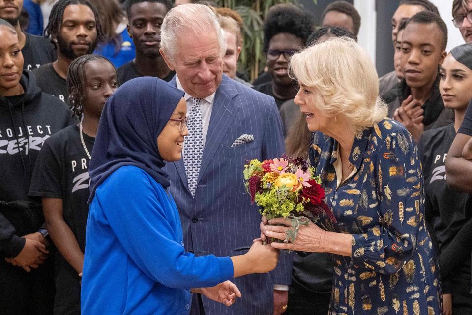 Britain's Camilla, Queen Consort (R), flanked by Britain's King Charles III (C), received a flower bouquet as she arrives to meet with members and staff of the association "Project Zero"