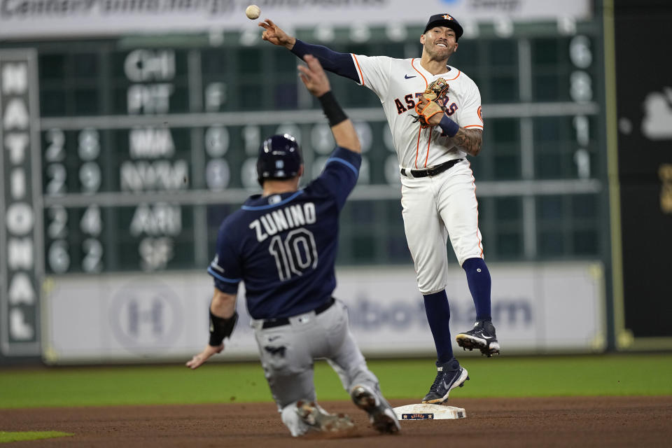 Houston Astros shortstop Carlos Correa, right, throws to first for a double play as Tampa Bay Rays' Mike Zunino (10) slides into second base during the seventh inning of a baseball game Tuesday, Sept. 28, 2021, in Houston. Tampa Bay Rays' Kevin Kiermaier was out at first and Zunino was out at second on the double play. (AP Photo/David J. Phillip)