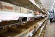 A shopper wearing a protective face mask, following an outbreak of the coronavirus disease (COVID-19), is seen next to empty shelves at a supermarket in Tokyo