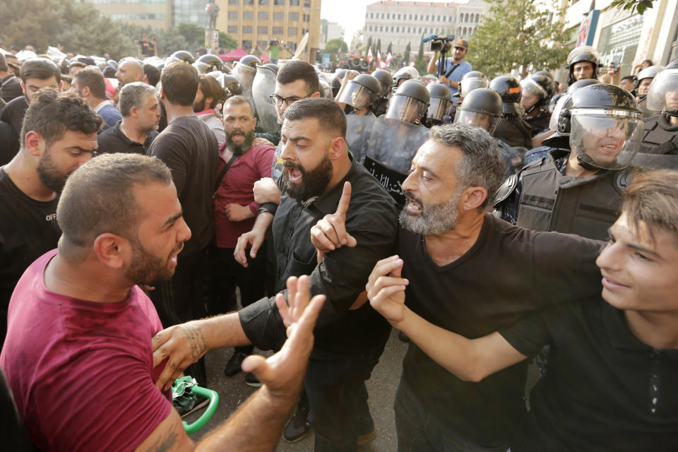 Hezbollah supporters try to calm down their commander after clash with Lebanese riot policemen during a protest in Beirut, Lebanon, Friday, Oct. 25, 2019. Leader of Lebanon's Hezbollah calls on his supporters to leave the protests to avoid friction and seek dialogue instead. (AP Photo/Hassan Ammar)